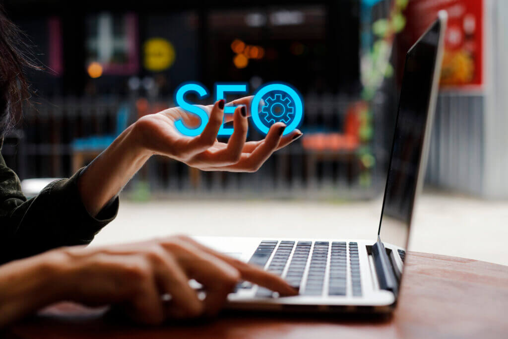 side view of hands on a laptop with the word SEO in blue cupped in one hand