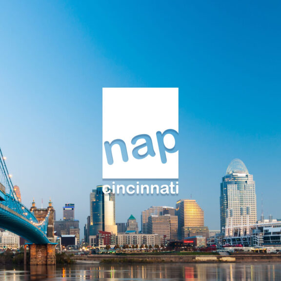 Image of downtown Cincinnati's skyline with a white nap cincinnati brand logo in the center of the image