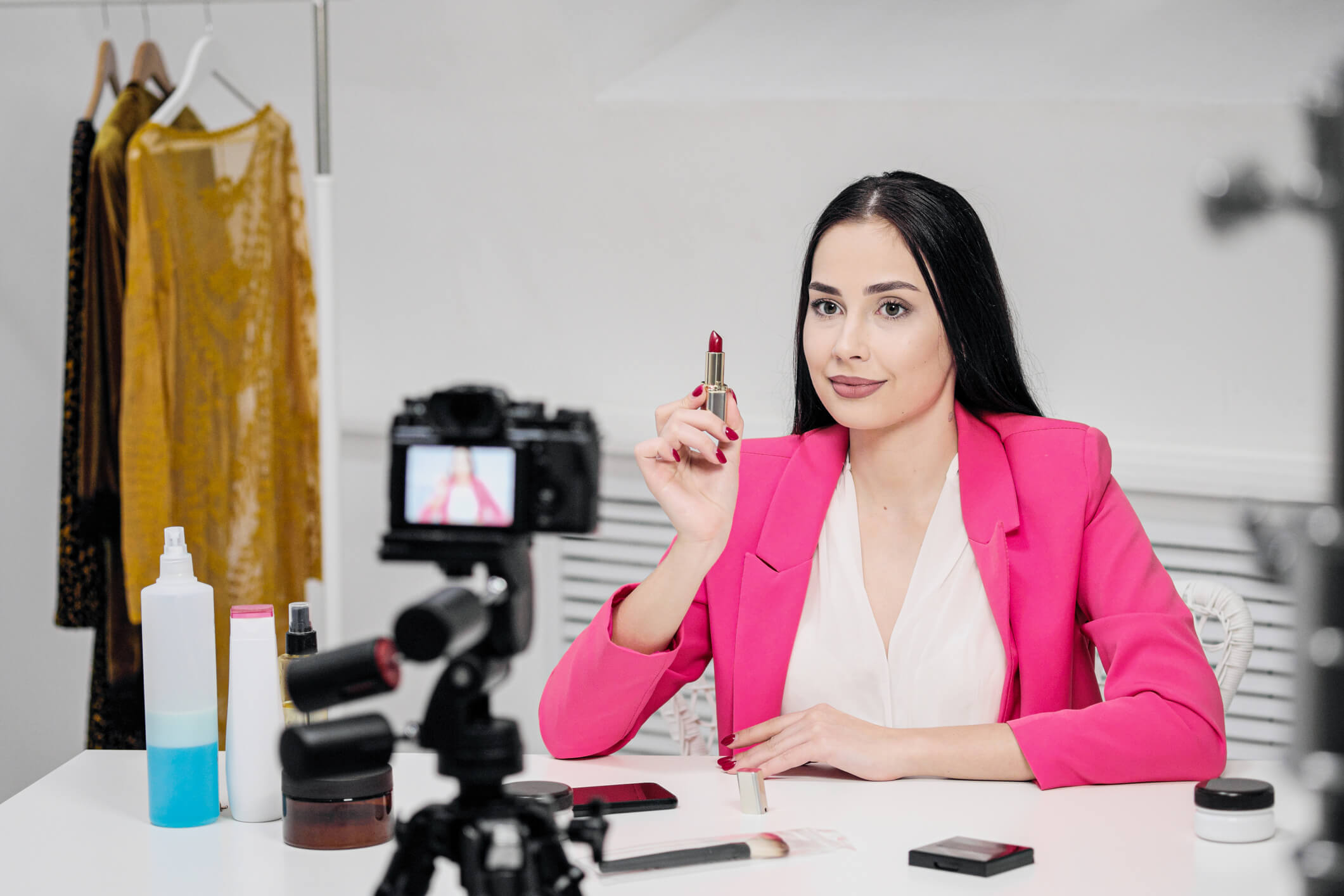 Image of an influencer holding up a lipstick as they create a video showcasing the product