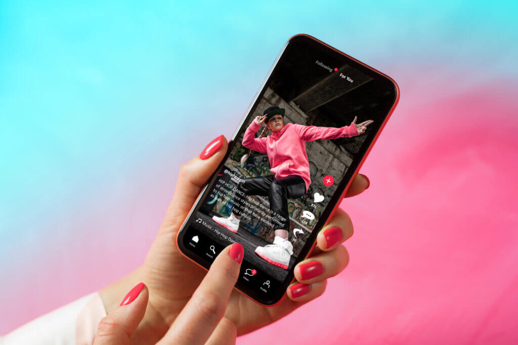 Pink and blue graphic with an image of a person’s hands holding a red phone with an Instagram reel pulled up on the screen
