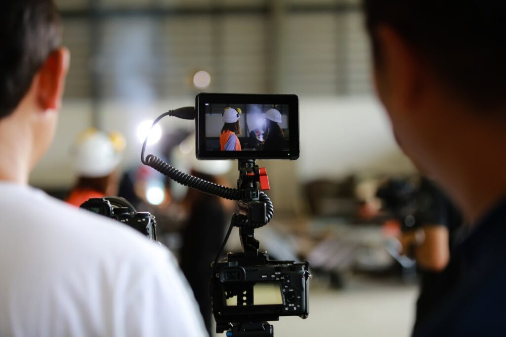 Photo of two men on a media team recording employees for a manufacturing plant