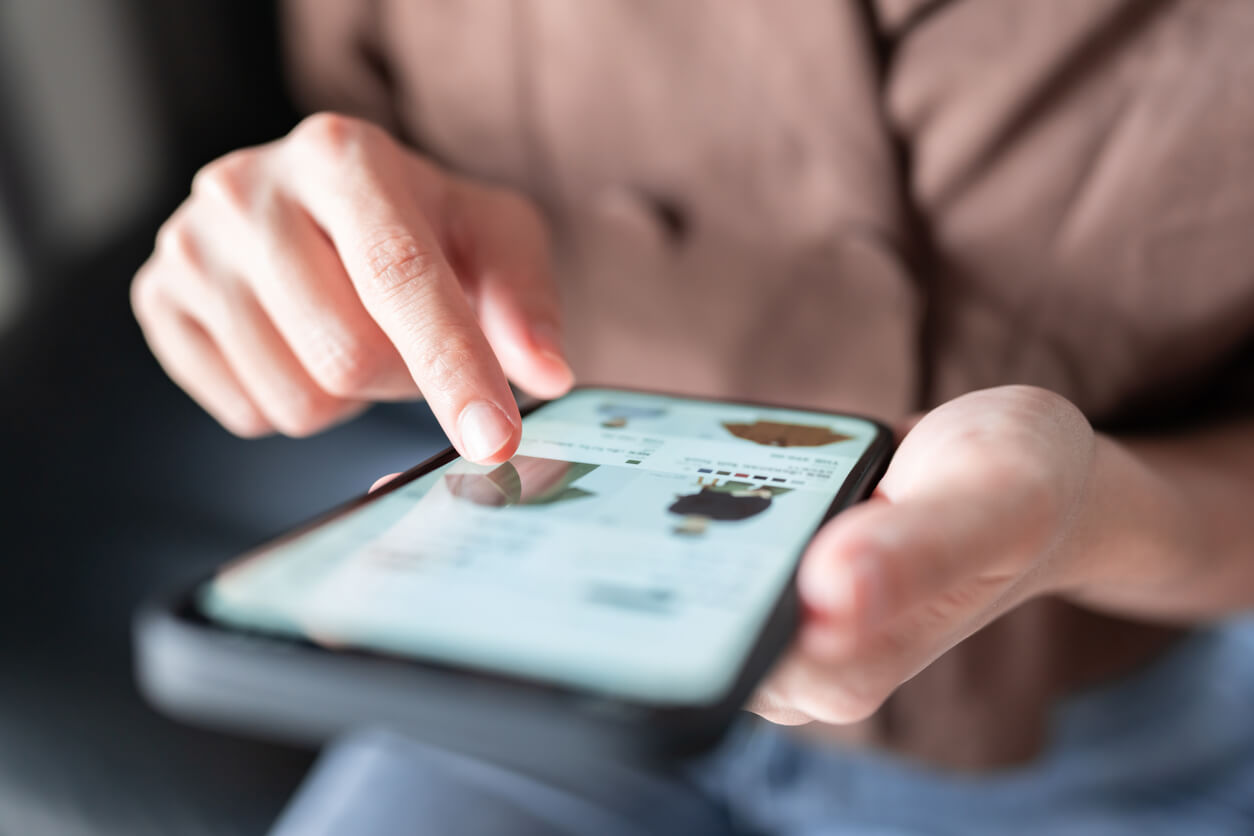 Photo of a smartphone with an e-commerce clothing website open as someone scrolls with their finger